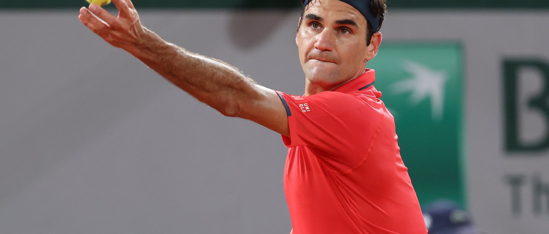 Federer in red shirt on court, holding tennis ball