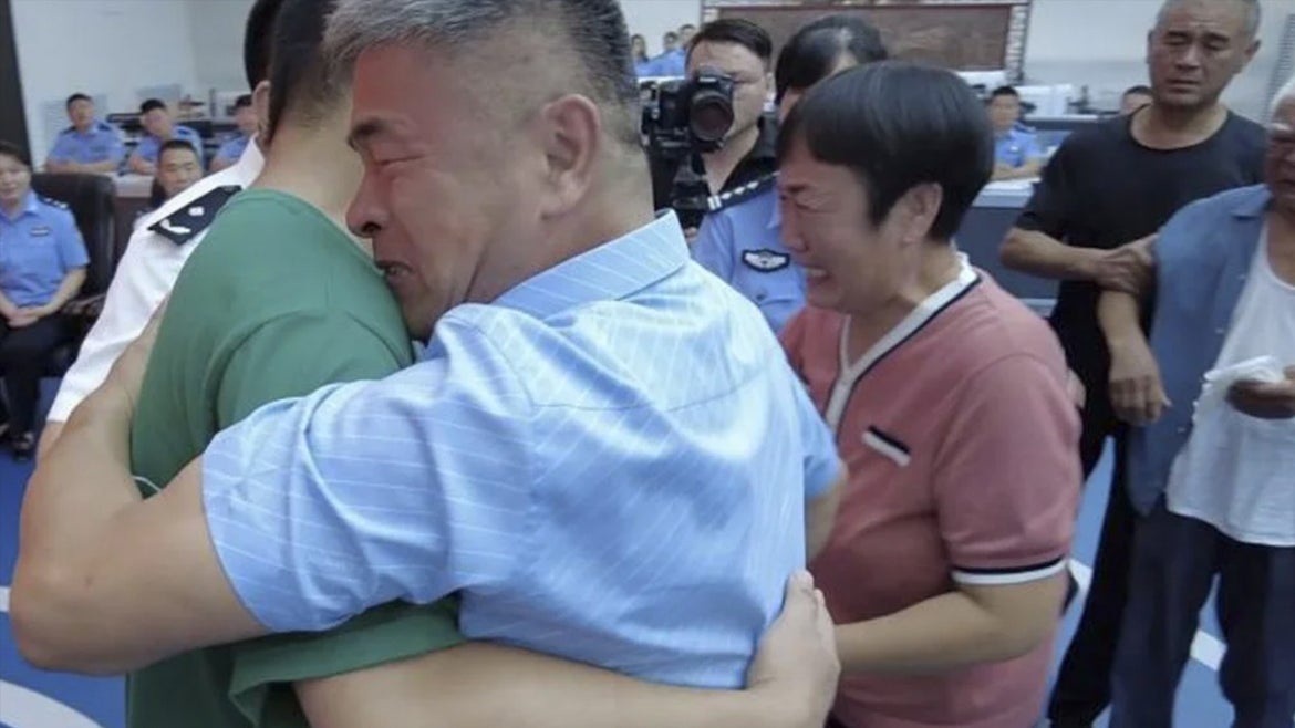Guo Gangtang and his son Guo Xinzhen embrace at their reunion.