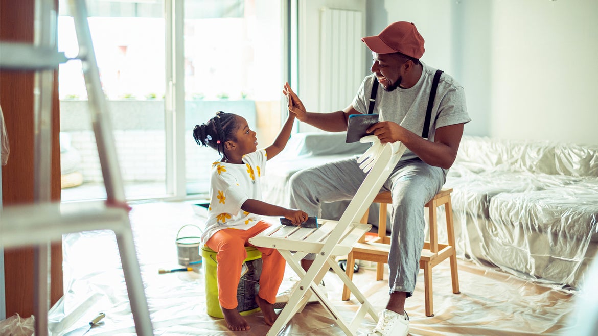 Close up of a father and his daughter painting a chair