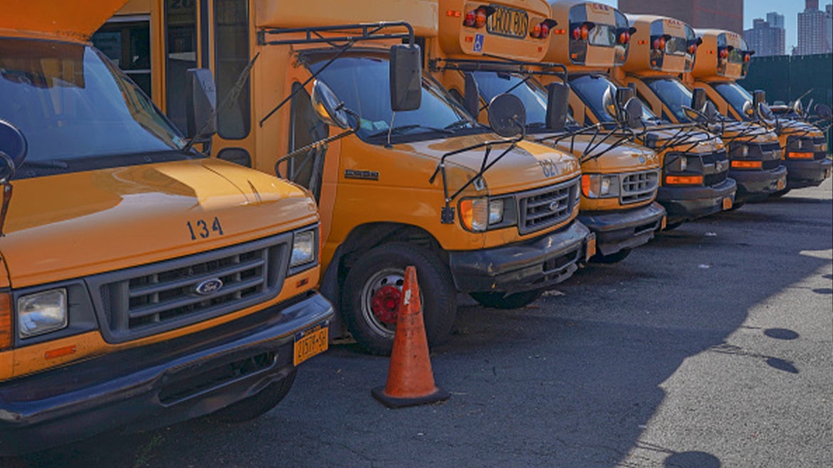 A stock image of school buses lined up in parking lot. 
