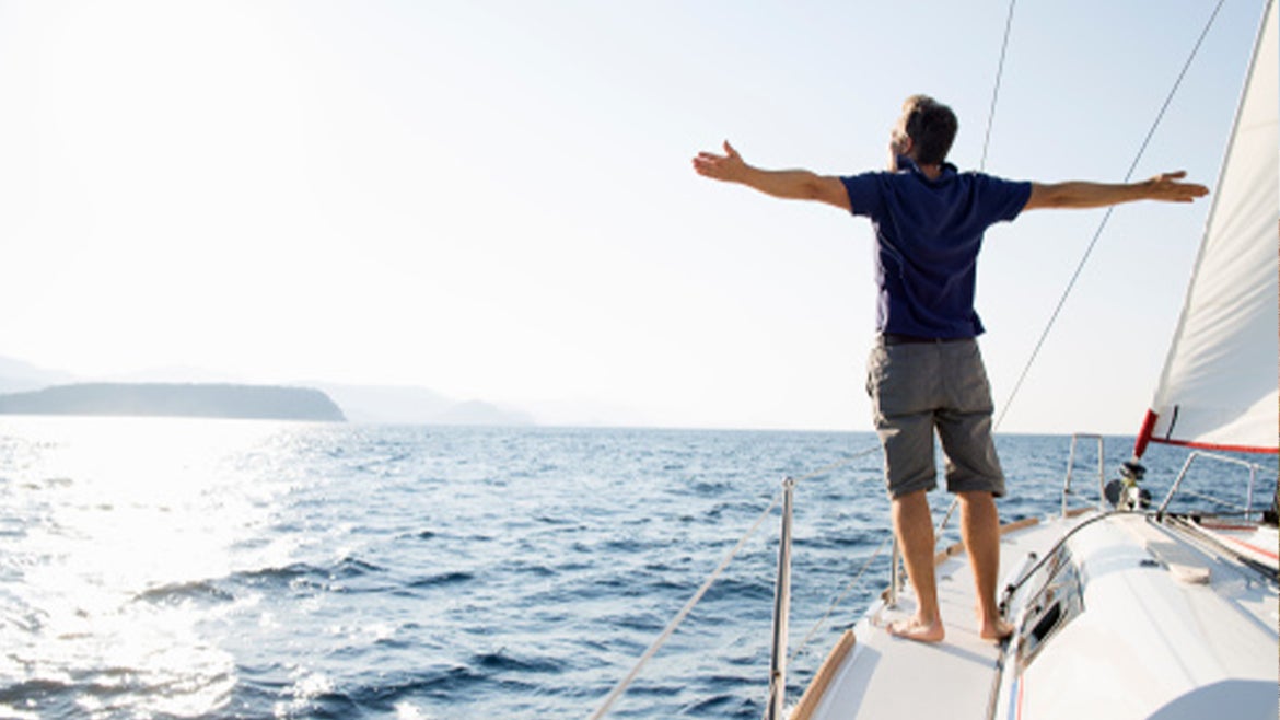 A stock image of a man enjoying himself on a boat in the ocean.