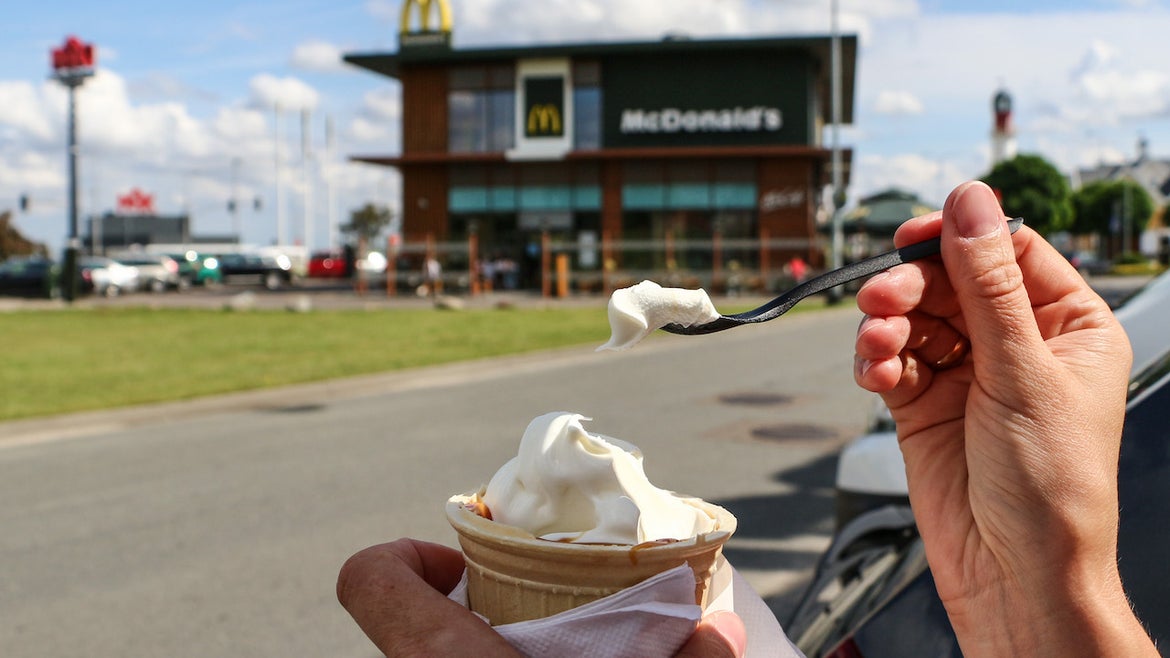Girl eating an ice-cream outside the McDonalds McDrive restaurant 