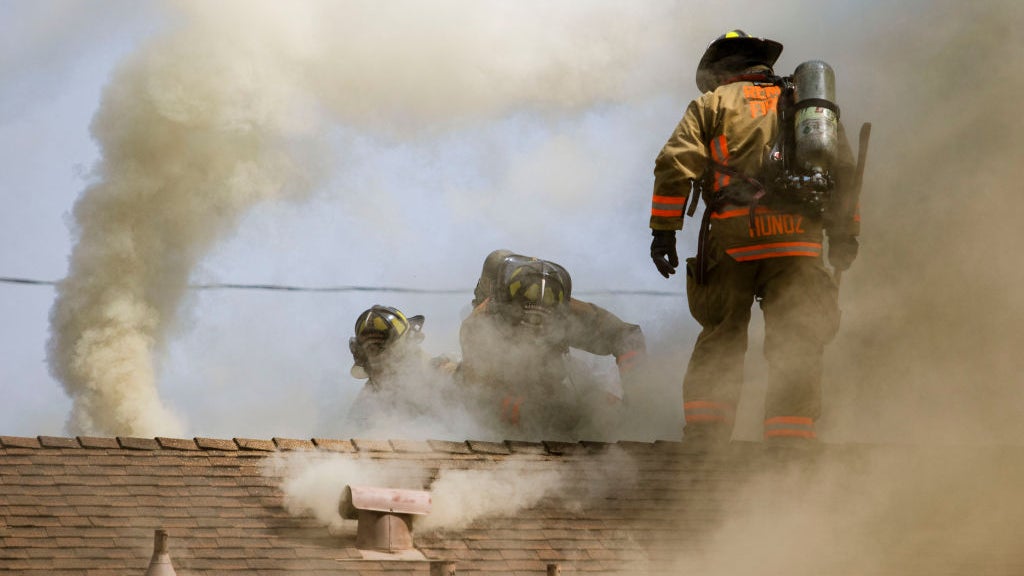 Firefighters on a roof with smoke