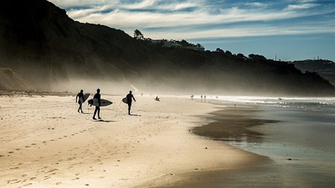 A stock image of surfers on a California beach.