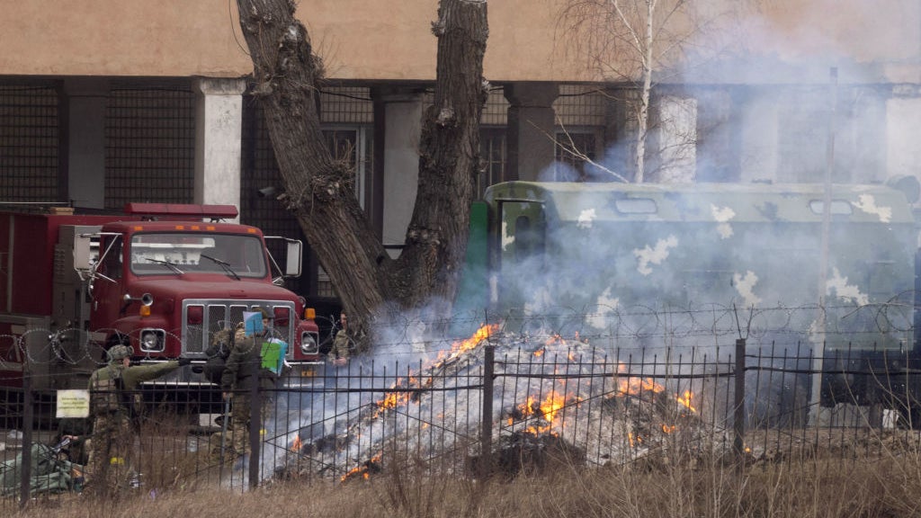 Military personnel throw items into a fire outside an intelligence building on February 24, 2022 in Kyiv, Ukraine.