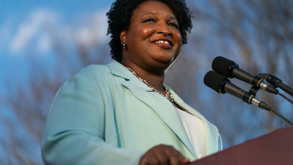 Stacey Abrams at a microphone smiling