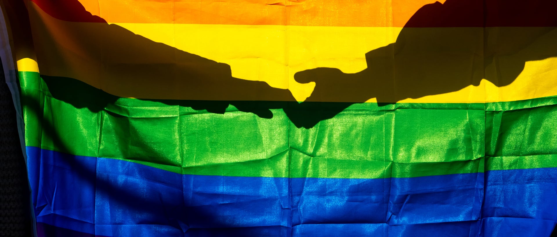 LGBTQ Pride flag with shadow of hands behind