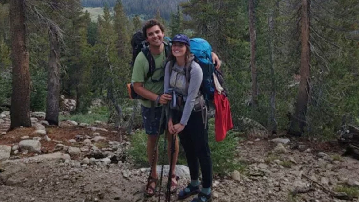 Dillen and Jenn Maurer standing for smiling photo while carrying hiking gear