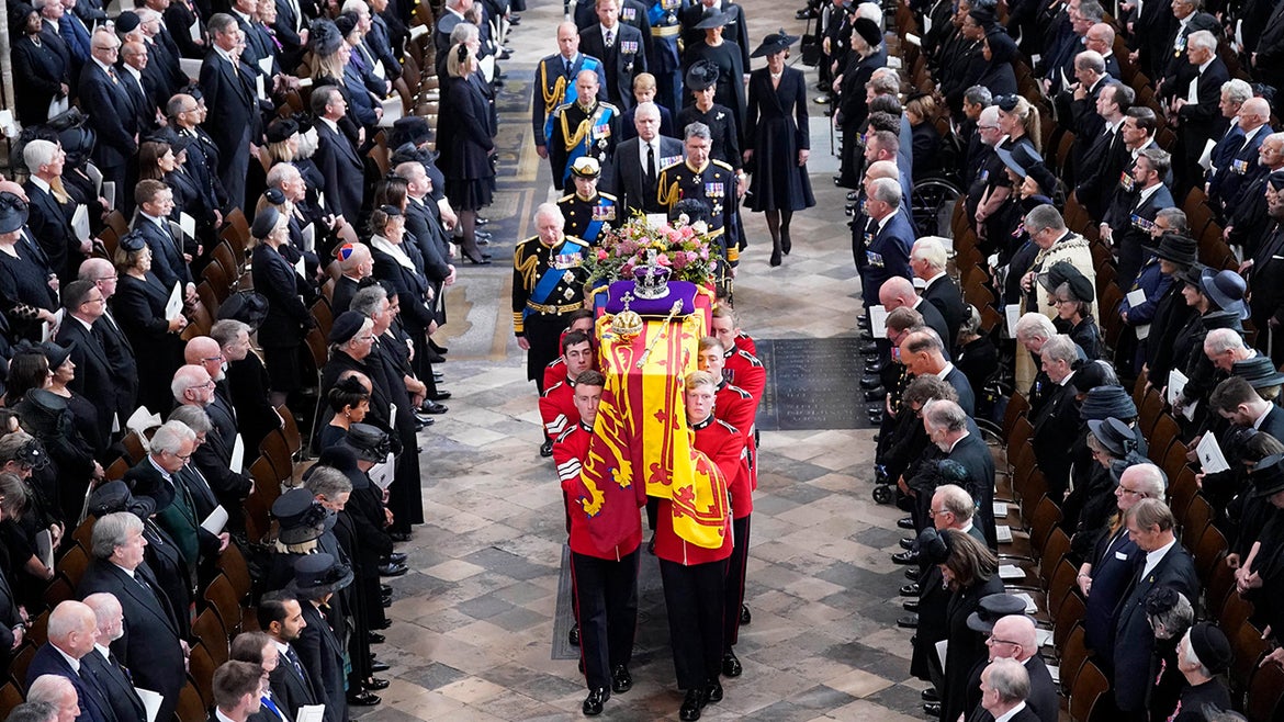 Queen Elizabeth's coffin being held by guards and members of the royal family walk behind it