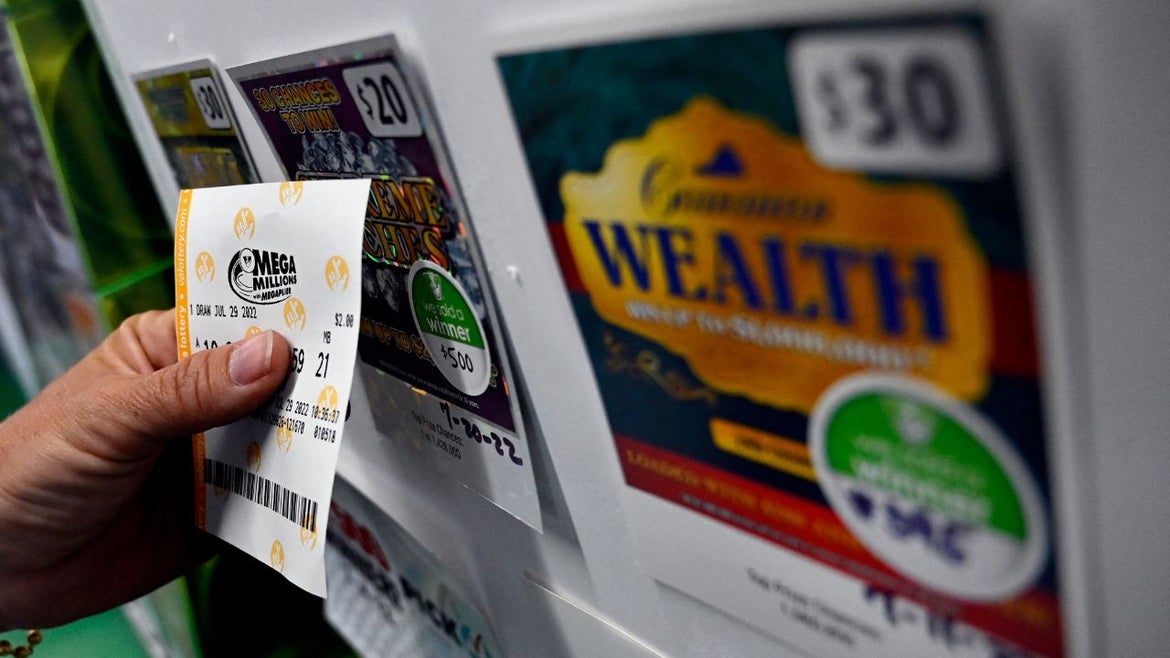 A person buys a Mega Millions lottery ticket at a store