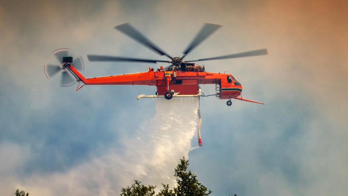 A red fire fighting helicopter drops water on a wild fire in Southern California