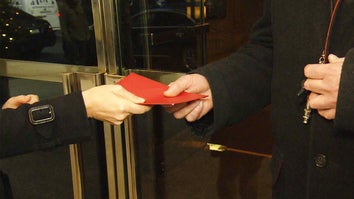 Close up of a hand passing a red envelope to another hand.