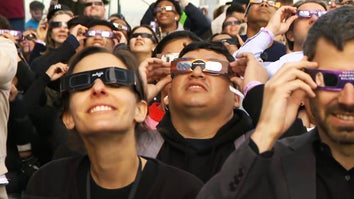 Crowds watch the solar eclipse through protective glasses.