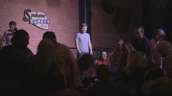 Comedian Drew Lynch watches from the stage as an audience member needs assistance