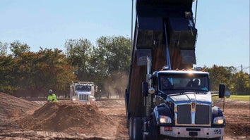 Large construction truck dumping its contents into a pile of dirt