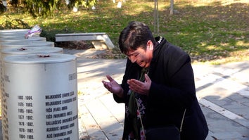 Fatima Popovac, a middle-aged white woman, kneels before memorial, in tears