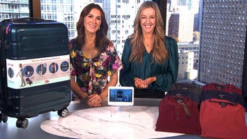 Two women standing behind a table displaying Spinner Luggage, Photo Frame, Shirts