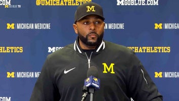 Coach Sherrone Moore being interviewed in front of a step-and-repeat