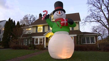 Large inflatable snowman decoration standing as tall as the house behind it