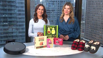Two women standing behind a table displaying a Robot Vacuum, Game Bundle, Slippers
