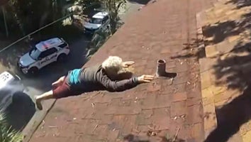 Older man clinging to rooftop as his legs dangle off