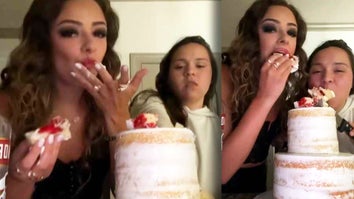 Two women cutting into a wedding cake and eating it