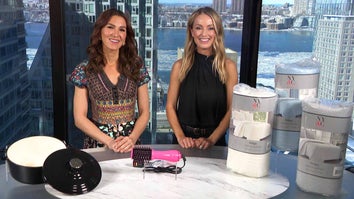 Two women standing behind a table displaying a Dutch Oven, Volumizing Brush, Quilt Set