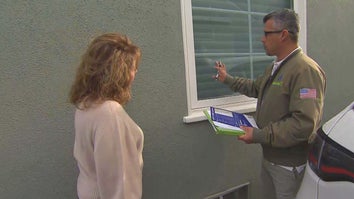 Woman watching as a home inspector points to an exterior window of a house