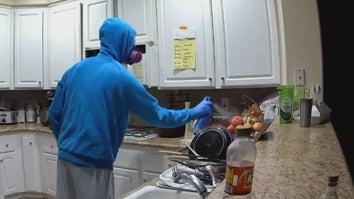Man in blue hoodie and protective mask spraying bug spray in kitchen