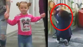 Girl holding adults' hands, teacher kneeling to check out child