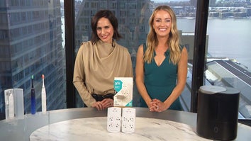 Two women standing behind a table displaying an Electric Toothbrush, Surge Protector, Humidifier