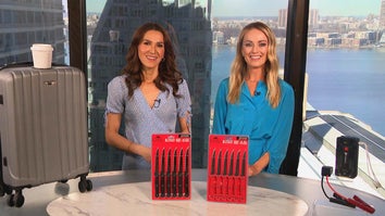 Two women standing behind a table displaying a Carry-On Luggage, Knife Set, Jump Starter