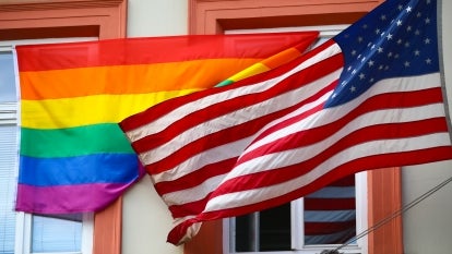 Pride flag next to the American Flag in front of building