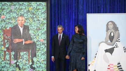 The Obamas standing in the middle of the portraits