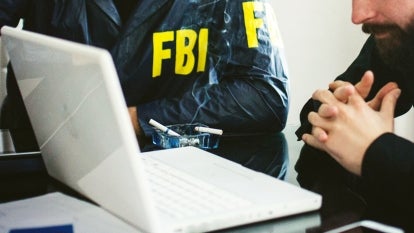 Unidentified FBI officers looking at a computer screen.