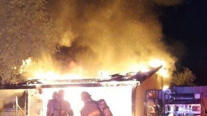 Firefighters standing in front of house in flames