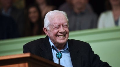 Jimmy Carter smiling sitting at podium