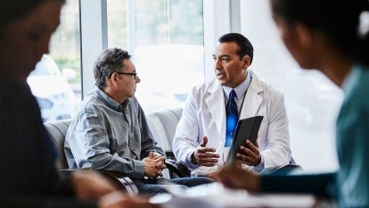 Male doctor discussing with male patient at lobby of medical clinic