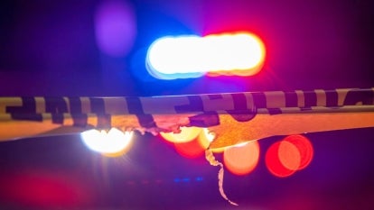 Yellow police tape with red and blue glowing police lights in the background