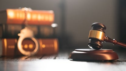 Glittering handcuffs on books and law hammer