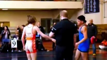 two teenagers in wrestling uniforms looking like they are about to shake hands