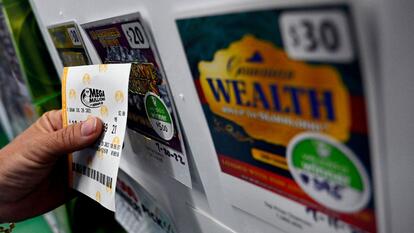 A person buys a Mega Millions lottery ticket at a store