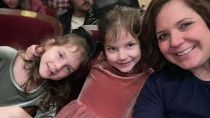 two young girls, including Aubrey Scaletta, sitting and smiling next to mom
