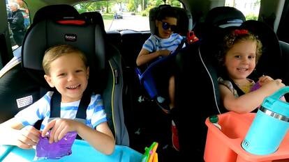 Three smiling children in car