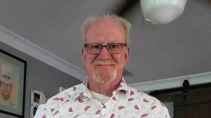 John Materna, 76, smiling wearing a white button-up with little slice watermelons on it