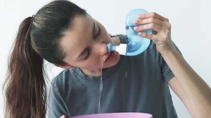Women clearing out her nasal passages using a neti pot.