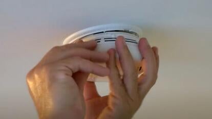 Hands screwing smoke detector