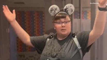 Woman wearing mouse ears with raised arms
