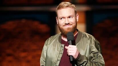 Comedian Kenny DeForest on Late Show stage, holding microphone