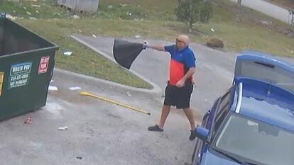 man throwing black bag into dumpster